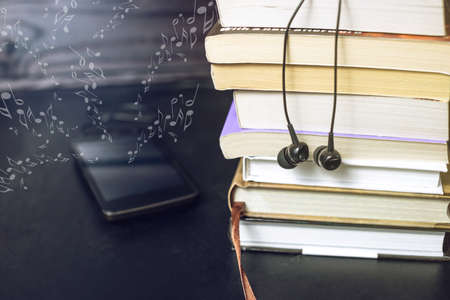 Black headphones on a stack of books and flying notes. The concept of audiobooksの写真素材