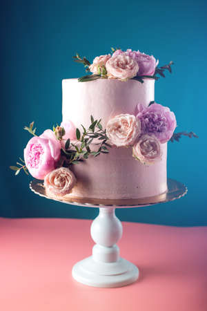 Bunk pink cream wedding cake decorated with fresh roses on a blue background. food design. trends.の写真素材