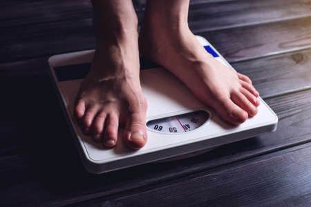 Women's feet are on mechanical scales for weight control on wooden background. The concept of slimming and weight lossの写真素材