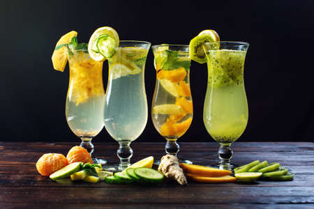 Set of cool fresh fruit lemonade with ice in a glass hurricane with tropical fruits on wooden background. The concept of summer drinks cocktailsの写真素材