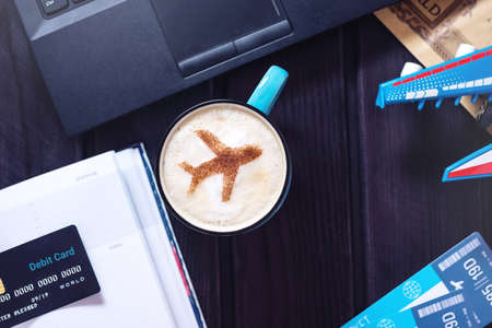 Laptop, plane tickets, coffee, cappuccino and credit card lies on the table. The view from the top. The concept of travel and transportの写真素材