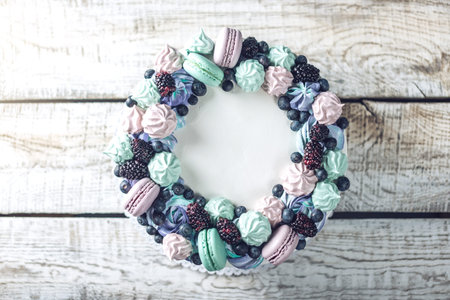 Homemade colorful cake with berries blackberries and blueberries decorated on top with meringue and marshmallows in a rustic styleの写真素材