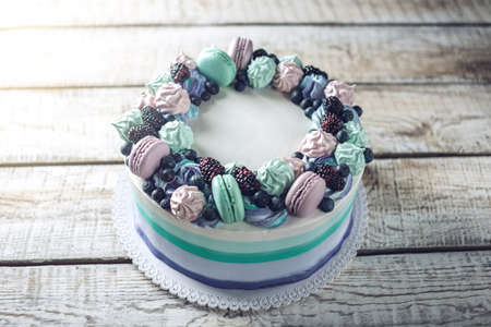 Homemade colorful cake with berries blackberries and blueberries decorated on top with meringue and marshmallows in a rustic styleの写真素材