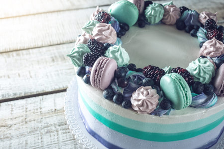Homemade colorful cake with berries blackberries and blueberries decorated on top with meringue and marshmallows in a rustic styleの写真素材