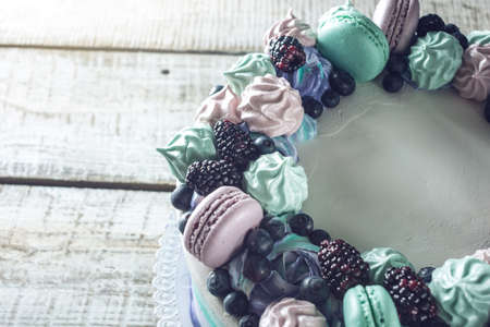 Homemade colorful cake with berries blackberries and blueberries decorated on top with meringue and marshmallows in a rustic styleの写真素材