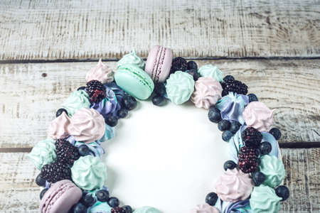 Homemade colorful cake with berries blackberries and blueberries decorated on top with meringue and marshmallows in a rustic styleの写真素材