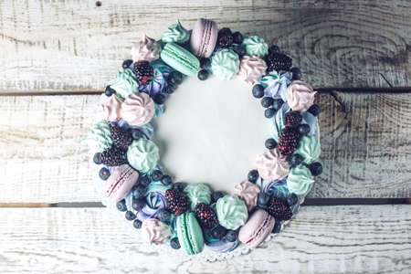 Homemade colorful cake with berries blackberries and blueberries decorated on top with meringue and marshmallows in a rustic styleの写真素材