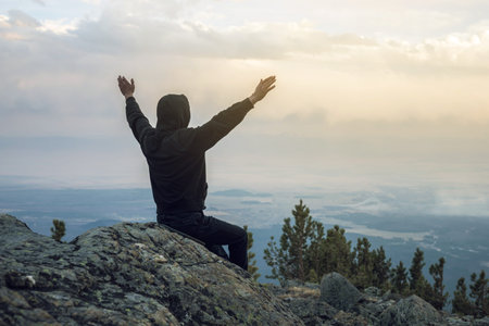 Man is sitting on a stone hillside, hands looking at the view from the heights and enjoys the...