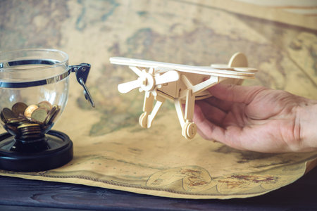 Toy wooden plane on a world map with open piggy Bank in a retro style. Concept of travel, discovery...