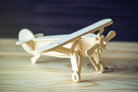 Wooden toy airplane flies on a dark background in retro style. The concept of travel and airline...