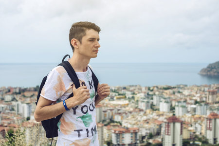 Man traveler with backpack explores the city looking at the panoramic view of the city and the...