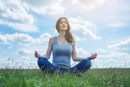 Woman traveler sitting on the meadow with green grass under blue sky with clouds in the Lotus...