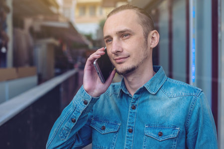 Man traveler with backpack talking on the phone in the background of the street. The concept of...