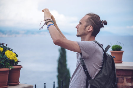 Man traveler with backpack makes a photo on your smartphone outdoors with mountains in the...