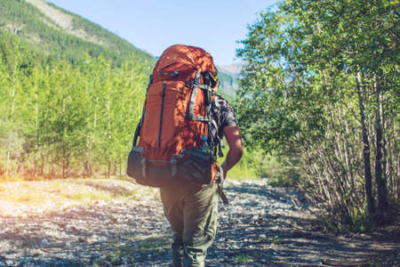 Healthy Active man with backpack hiking in beautiful mountain forest in the summer in the sun. The concept of travel and Hiking in beautiful places of untouched natureの写真素材