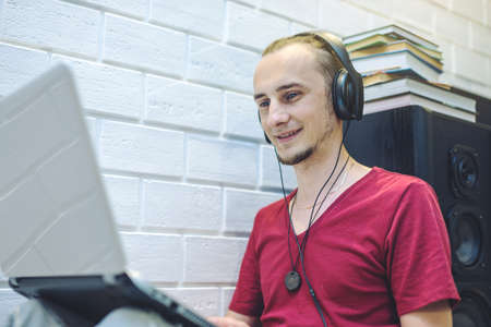 Young man with headphones listening to lessons and working at a laptop in a multimedia home atmosphere. the concept of technology and modern educationの写真素材