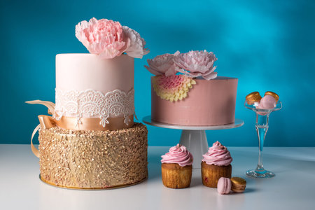 Luxury wedding table with a beautiful pink cake decorated with mastic pink rose and gold on a blue background. the concept of chic wedding dessertsの写真素材
