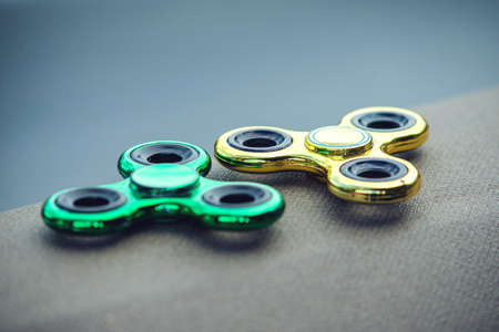 Green and golden fidget spinner stress relieving toy. Trends in children's anti-stress toys for attentionの写真素材