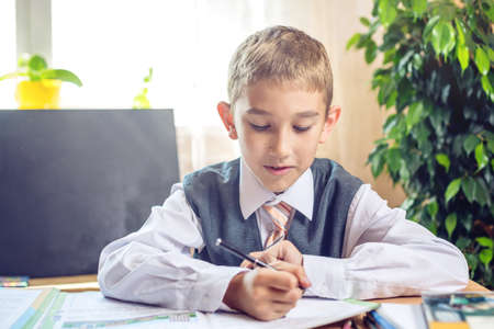 Back to school. Cute child sitting at the desk in the classroom. Boy is learning lessons. Concept for the first time in elementary schoolの写真素材