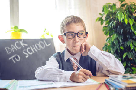Back to school. Cute child sitting at the desk in the classroom. Boy is learning lessons. Concept for the first time in elementary schoolの写真素材