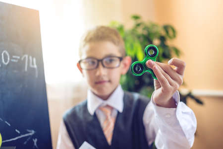 Back to school. Cute child sitting at the desk in the classroom. Boy playing with a spinner during the lesson. Concept for the first time in elementary schoolの写真素材