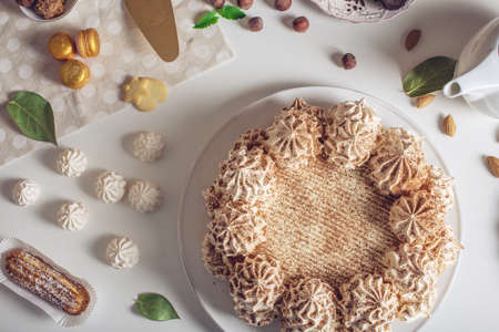 Beautifully decorated dessert table where the cake with meringue, layered pieces of cake on a white table. Arrangement of delicious sweets, top viewの写真素材