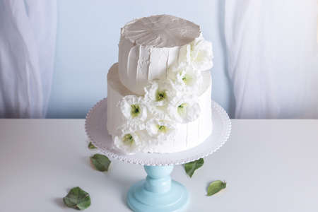 White bunk wedding cake decorated with flowers on a blue bookcaseの写真素材