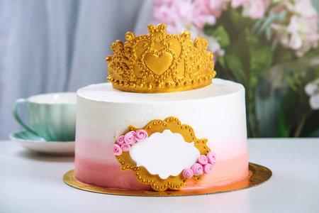 Cute cake with a gold crown on the table with cups to the birthday for a Princess. Place for text