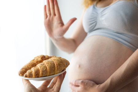 A pregnant woman with belly refuses to croissants. The concept weight control and an unhealthy diet during pregnancyの写真素材