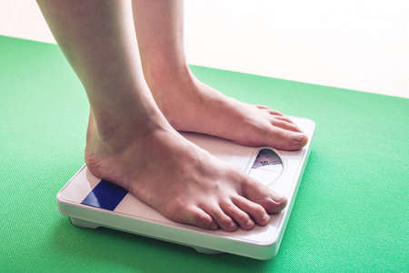 Female feet standing on mechanical scales for weight control. The concept of slimming and weight lossの写真素材