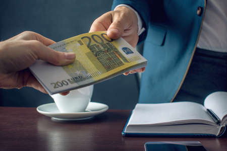 Man Businessman in suit takes the money hands. A bribe in the form of euro bills. The concept of corruption and briberyの写真素材