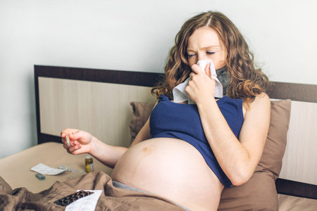 Young pregnant woman in bed with pills and a thermometer. Sick with the flu or a cold.