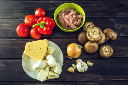 Ingredients for pizza on the dark wooden table.Chicken fillet, mushrooms. onions, tomatoes. The concept of eco-friendly products for cookingの写真素材