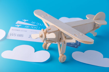 Wooden toy airplane and tickets on a background of blue sky with paper clouds. The concept travel...
