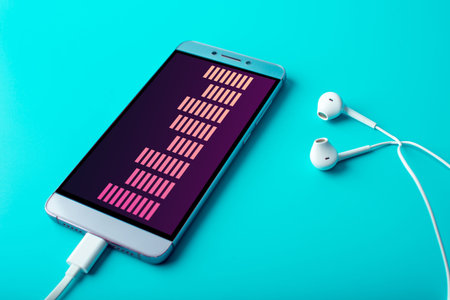 Phone with white earphones on blue background. The concept of modern music and technology