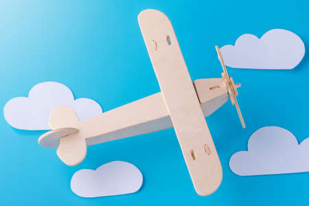 Wooden toy airplane on a background of blue sky with paper clouds. The concept travel and airlinesの写真素材