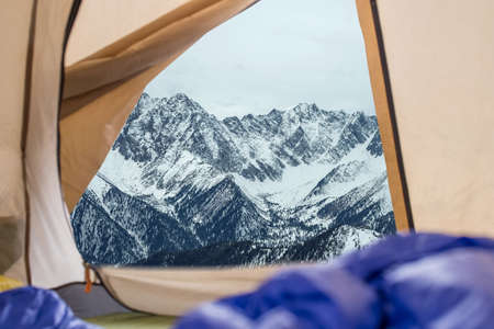 View from tent on snow-capped mountains. Trips and expeditions in the wild. The concept of campingの写真素材