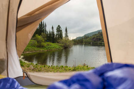 View from tent on a mountain lake. Trips and expeditions in the wild. The concept of campingの写真素材