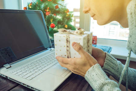 Man holding a gift for Christmas and new year booking over the Internet in the laptop. The concept of holiday gifts and discountsの写真素材
