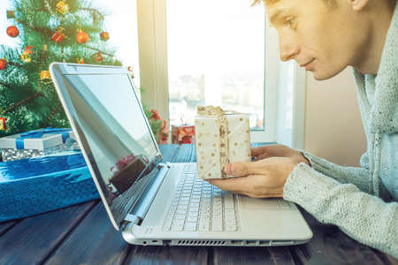Man holding a gift for Christmas and new year booking over the Internet in the laptop. The concept of holiday gifts and discountsの写真素材