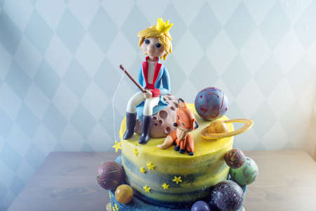 Big kids beautiful cake decorated in the form of the planet with the mastic figurines of the little Prince and the Fox. The concept of festive desserts for the birthday childrenの写真素材