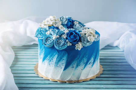 Beautiful blue wedding cake decorated with white flowers of cream with a place for a label. The concept of Holiday desserts for a birthdayの写真素材