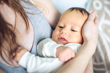 Happy caring mother holding a smiling baby boy in the bedroom. The concept of the tenderness of...