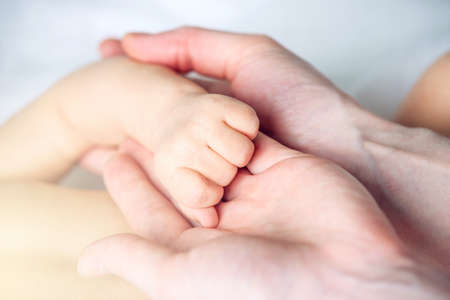 Mother holding the hand of a baby. The concept of empathy, trust, care and tenderness of motherhoodの写真素材