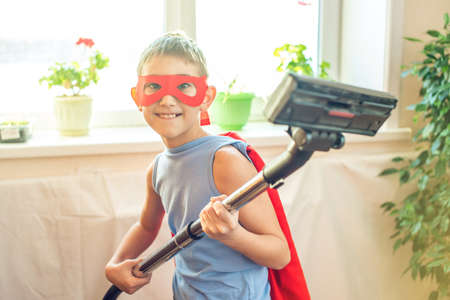 Boy child superhero costume playing is cleaning the house. The concept of children helping their parents in the form of a gameの写真素材