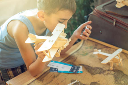 Happy boy child with toy airplane and compass in hand, explore the map below to travel to new adventures.の写真素材