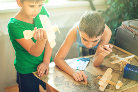 Happy children boys with a toy airplane and compass in hand, explore the map below to travel to new adventures.の写真素材