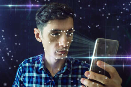 Man is trying to access the phone using the personal identification method of face recognition according to the polygonal mesh. The concept of modern technologyの写真素材