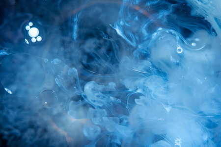 Swirls of white paint moving in the water like smoke on a dark background. Concept abstract...