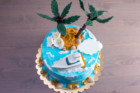A beautiful birthday cake decorated in an island with a palm tree in blue sea and boat